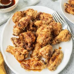 Crispy baked chicken wings with saucy glaze on white plate for easy sharing.