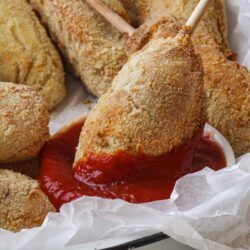 Crispy chicken drumsticks coated in bread crumbs with marinara sauce for dipping.