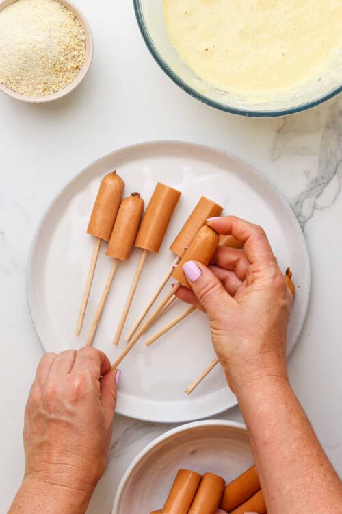 Creamy peanut butter popsicle on flat white plate with other ingredients in background.
