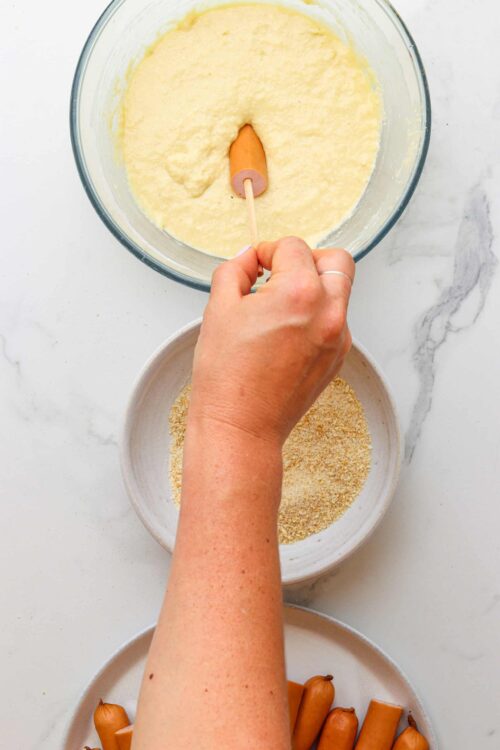 Golden cracker crumbs being sprinkled into a mixing bowl with batter for homemade baked goods.