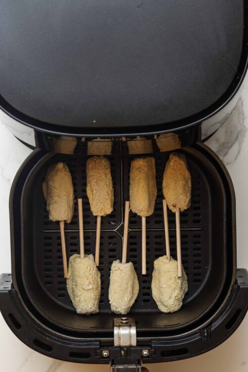 Fried chicken strips in an air fryer basket.