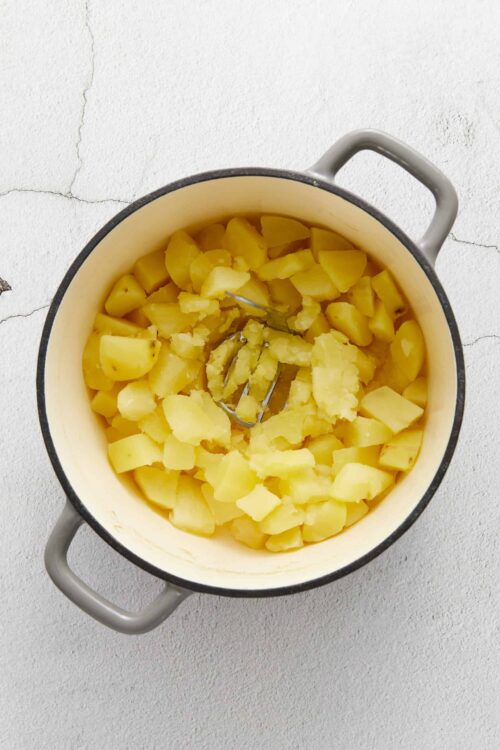 Creamy mashed potatoes in a white enamel pot, ready for baking or serving. Perfect comfort food or side dish.