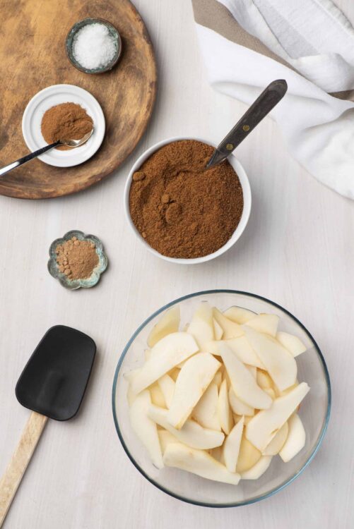 Sweet Potato Pie Spice Blend on white table with peeled sweet potatoes, salt, and spices.