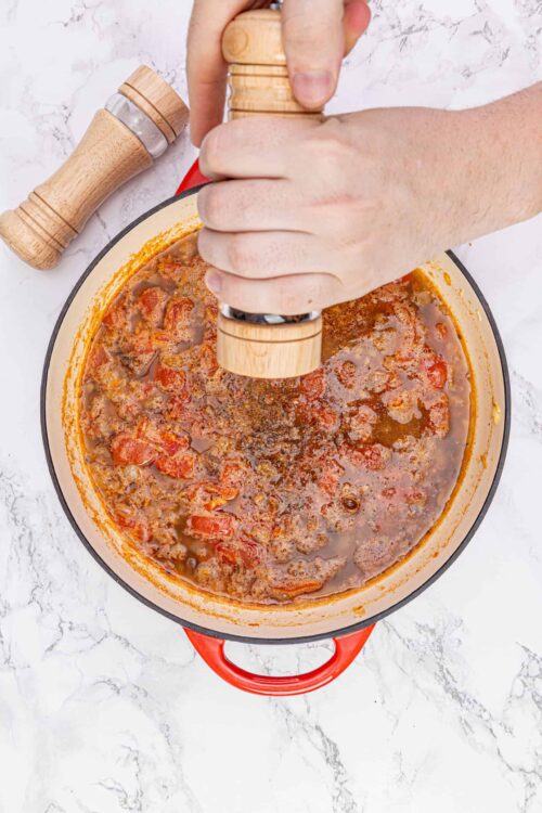 Seasoned beef and tomato sauce in a red Dutch oven.