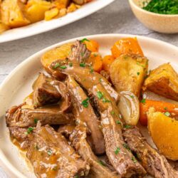 Tender beef short ribs with roasted root vegetables on a cozy dinner plate.