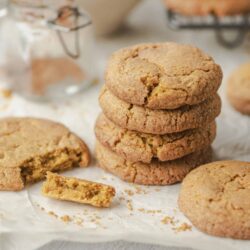 Soft and chewy peanut butter cookies on parchment paper with a cookie broken in half.