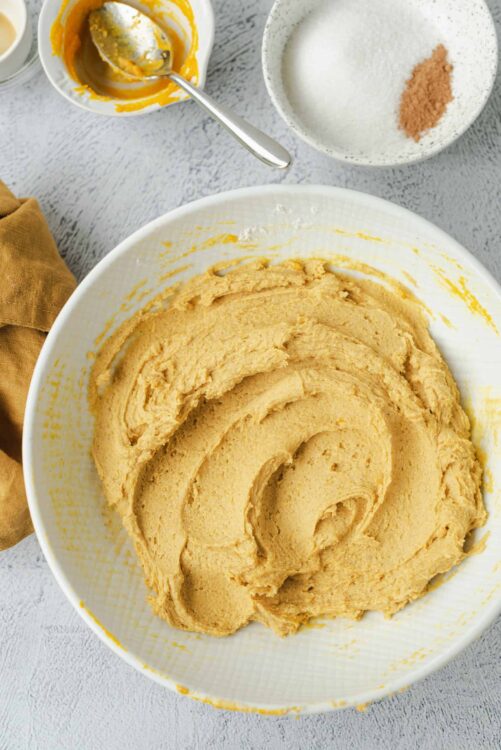 Creamy pumpkin pie filling in a white mixing bowl for homemade dessert.