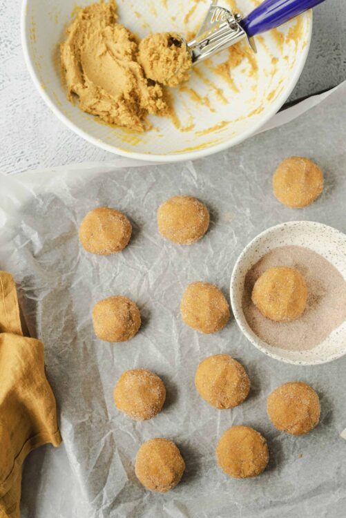 Creamy cookie dough in a mixing bowl with a purple-handled ice cream scoop.