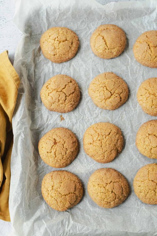 Soft sugar cookies with cracked tops, fresh baked and displayed on parchment paper.