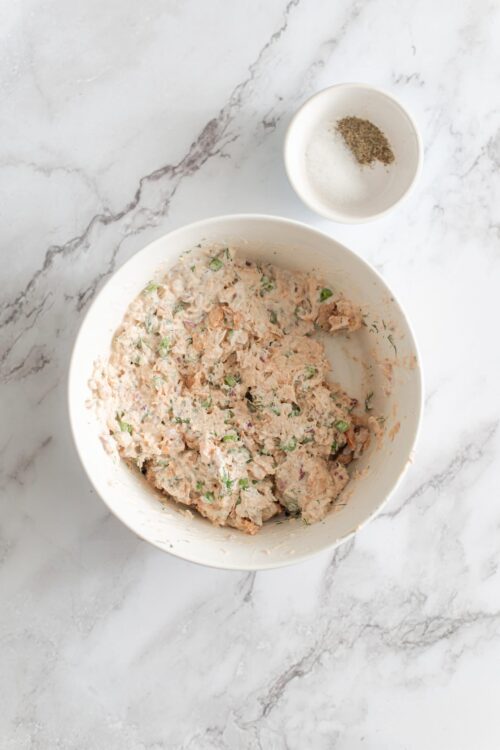 Creamy homemade tuna salad with herbs in a white mixing bowl, ready for serving.