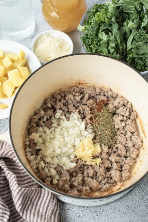 Ground beef cooking with onions, garlic, and spices in a Dutch oven.