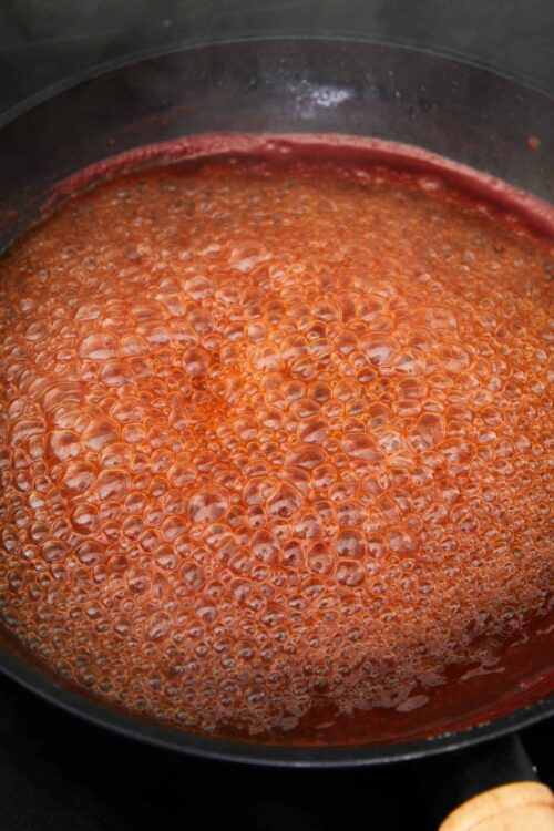 Sweet tomato sauce simmering in a black skillet, ready for pasta or pizza.
