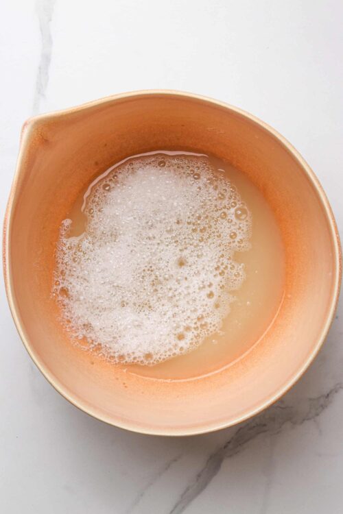 Freshly mixed batter with bubbles in a pink ceramic bowl for baking or cake making.