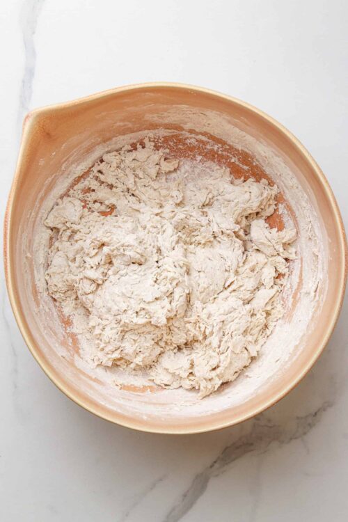 Creamy pie dough in a peach-colored mixing bowl, ready for baking.