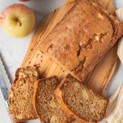 Sweet apple spice loaf cake on a wooden board with fresh apples, perfect for fall desserts.