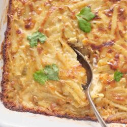 Creamy scalloped potato casserole with golden cheese crust and fresh parsley garnish.
