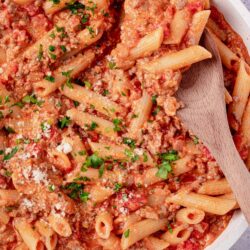 Creamy baked ziti with melted cheese, tomato sauce, and fresh herbs in a white baking dish.