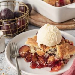 Golden cherry pie with vanilla ice cream on a white plate, baked dessert with fresh fruit, homemade fruit pie, baked bree style dessert.