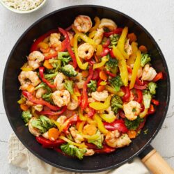 Sautéed shrimp and colorful vegetable stir-fry with broccoli, bell peppers, carrots, and red onions.