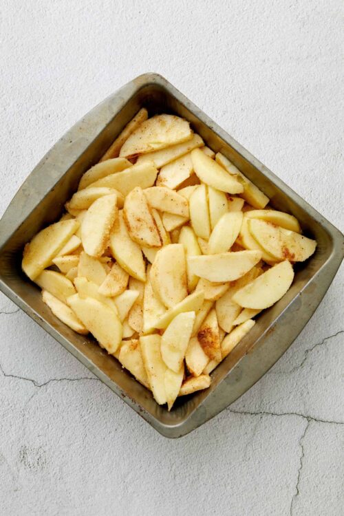 Sliced and peeled apples in a baking dish for homemade apple pie or crisp.