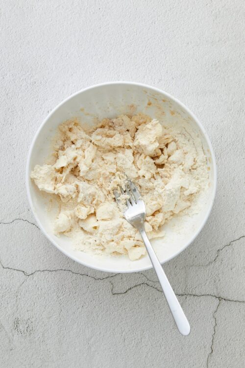 Cracked pie crust dough in a white mixing bowl ready for baking.