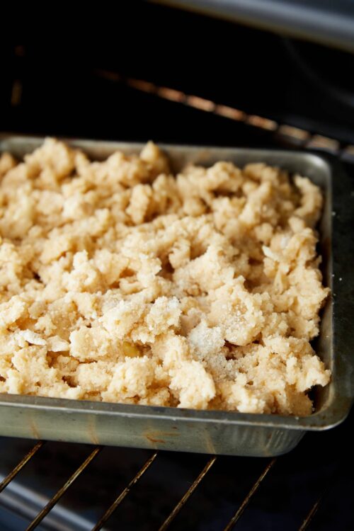 Golden crumb topping baking in a metal pan inside an oven.