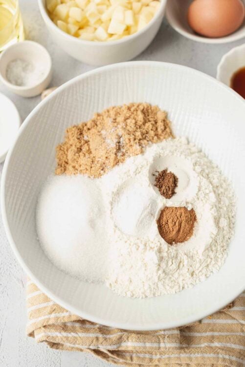 Flour, sugar, baking powder, and cocoa powder in a white mixing bowl for baking recipes.