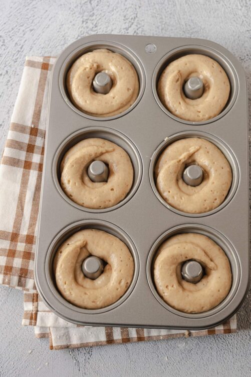 Freshly poured cinnamon roll batter in muffin pan ready for baking.