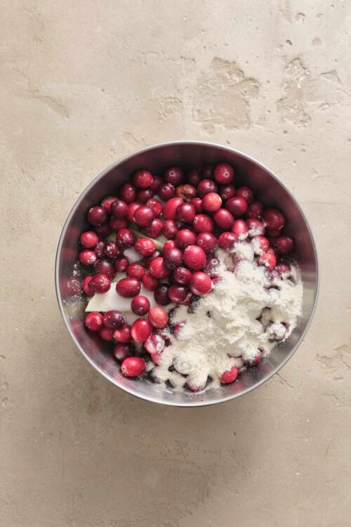 Fresh cranberries with flour and sugar in a mixing bowl for baking.