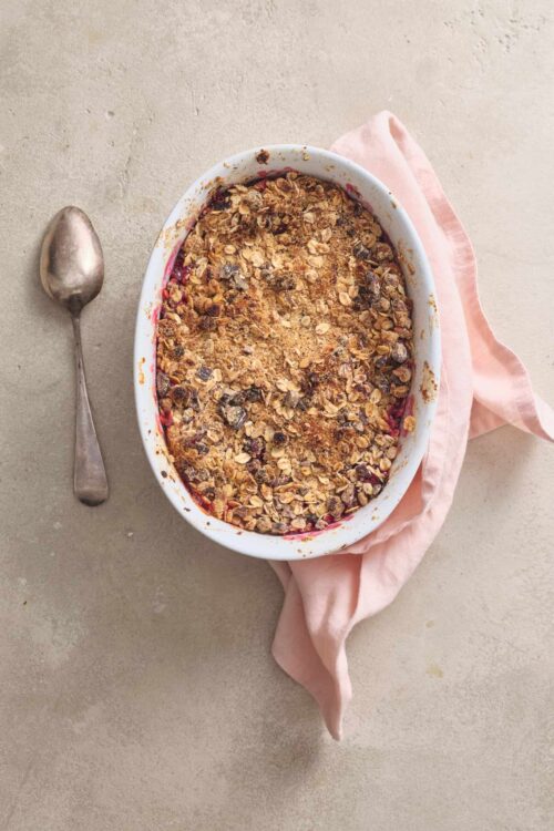 Crunchy berry crisp with oat topping in an oval baking dish, ready to bake or serve.