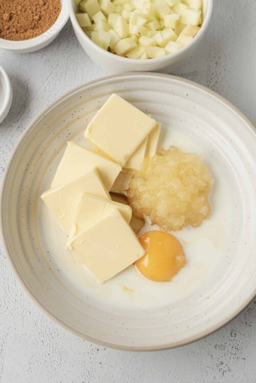 Cream cheese, butter, and eggs in a mixing bowl for baking recipes.