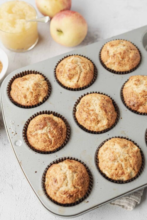 Fluffy homemade apple cinnamon muffins in a baking tin. Perfect for breakfast or snack, featuring fresh apples and warm cinnamon flavor.