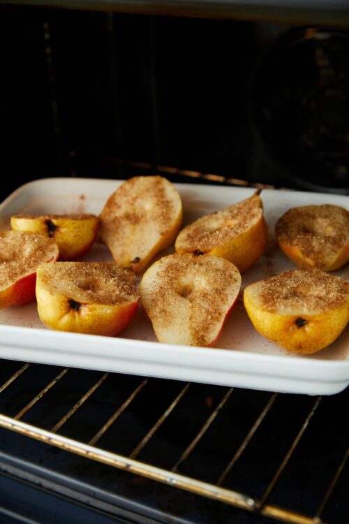 Baked apples with cinnamon sugar on a baking sheet in the oven.