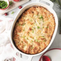 Baked chicken casserole with cheese and herbs in a white baking dish.