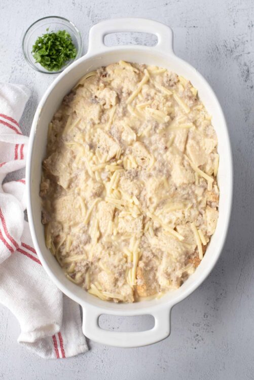Creamy chicken and biscuit casserole in a white baking dish with shredded cheese on top.