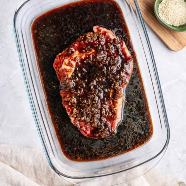 Marinated beef roast in rich soy sauce and garlic marinade, ready for roasting or grilling.