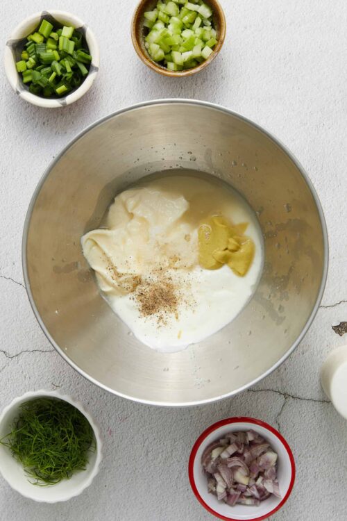 Cream cheese, sour cream, and mustard in a metal mixing bowl for a dip or sauce recipe.