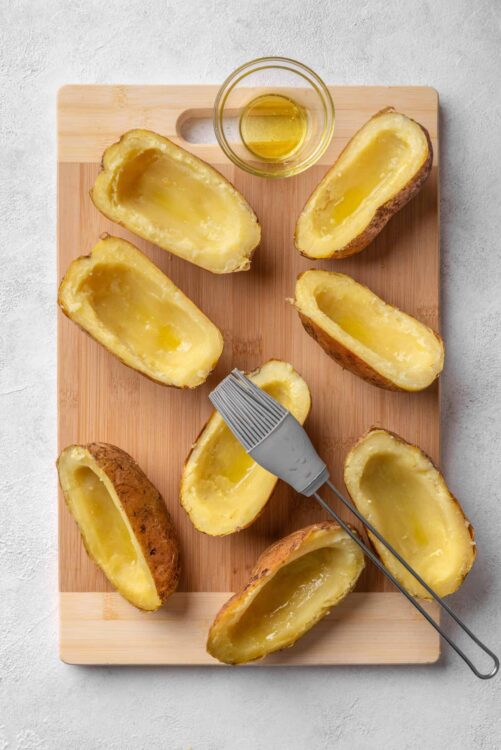 Baked potatoes with melted butter on a wooden cutting board.