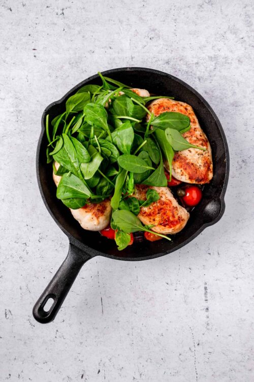 Juicy skillet chicken with fresh greens and cherry tomatoes.