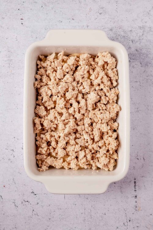 Crumble topping in a white baking dish, ready for baking or dessert preparations.