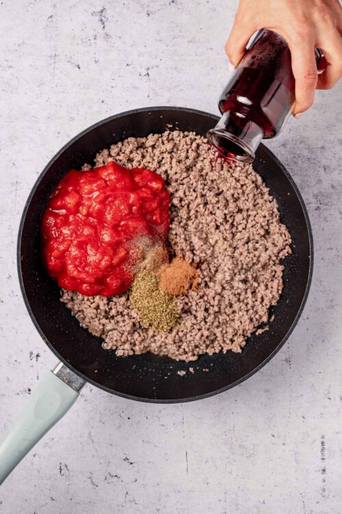 Ground beef cooking in a skillet with tomato sauce and spices, ready for a delicious homemade dish.
