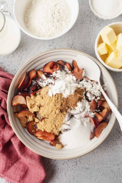 Fresh peach pie filling ingredients with flour, sugar, and butter in a baking dish.