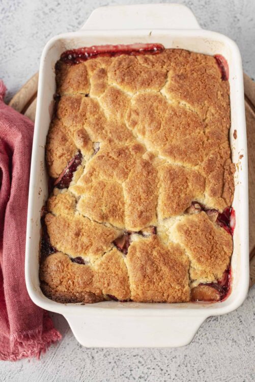 Buttermilk Cherry Cobbler with golden biscuit topping in a white baking dish.