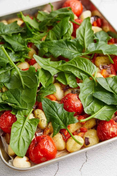 Fresh vegetable gnocchi casserole with cherry tomatoes and spinach, baked to perfection.