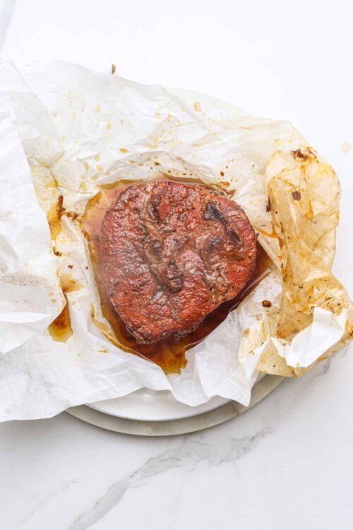 Juicy braised beef short ribs on parchment paper, ready to serve.