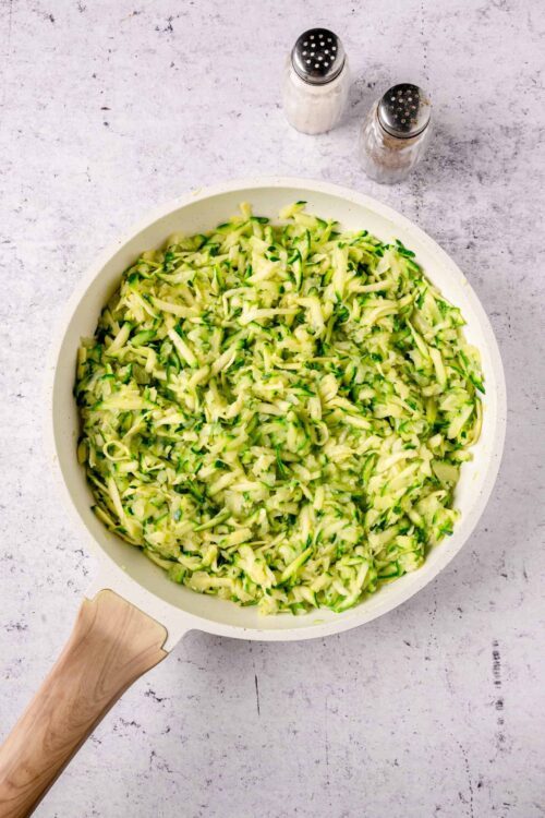 Freshly grated zucchini in a white mixing bowl, ready for baking or cooking. Perfect for healthy zucchini recipes from Baked Bree.