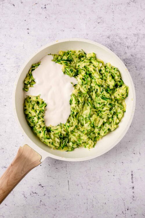 Zucchini noodles in a white skillet with cream cheese, fresh and healthy veggie pasta option.