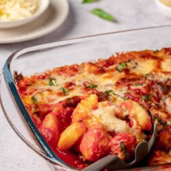 Roasted vegetable lasagna with cheese in a glass baking dish.