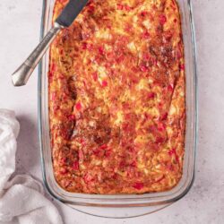 Baked cheesy chicken and rice casserole in a glass baking dish with a serving spatula.