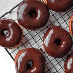 Chocolate glazed donuts on cooling rack, freshly baked bakery treats.
